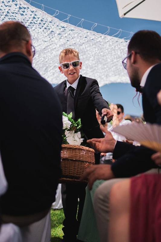 Junge mit Sonnenbrille verteilt Bl&uuml;ten an die G&auml;ste