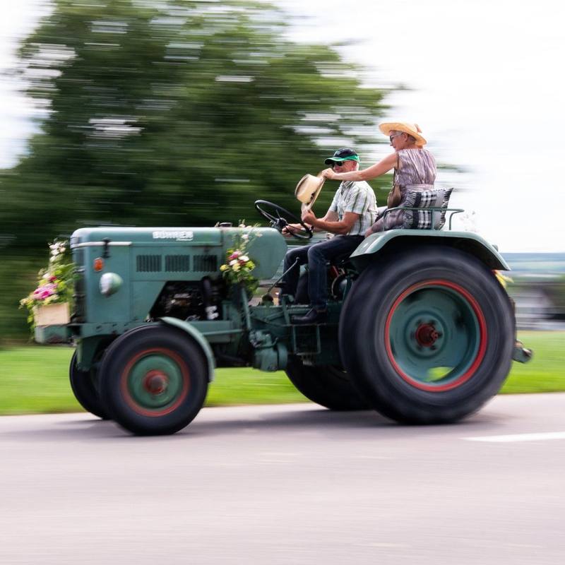 Brautpaar f&auml;hrt auf einem geschm&uuml;ckten Oldtimer-Traktor